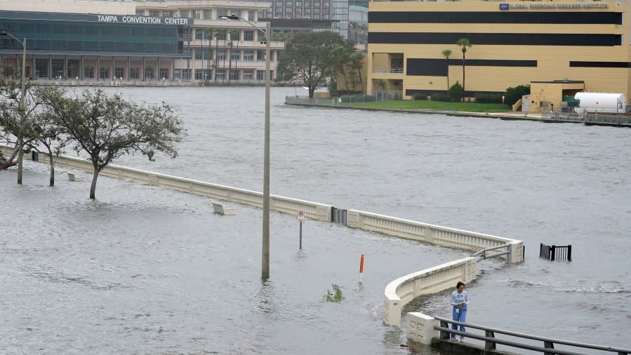 A woman surveys the flooding on Bayshore Blvd., along Old Tampa Bay after winds from Hurricane Idalia pushed water over the sea wall Wednesday, Aug. 30, 2023, in Tampa, Fla. Idalia made landfall earlier this morning along the Big Bend of the state. (AP Photo/Chris O’Meara)