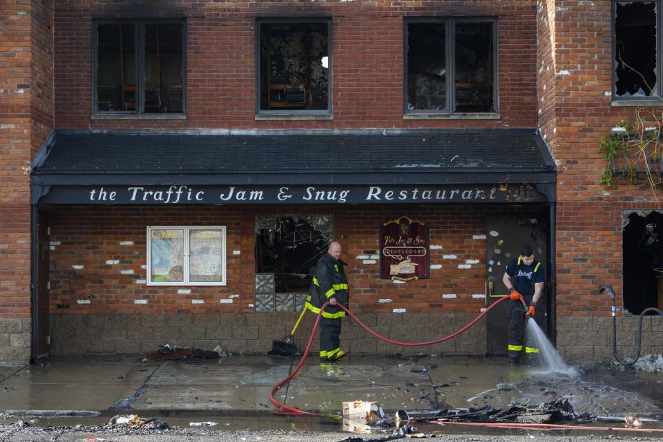 Detroit firefighters clean up in front of Traffic Jam and Snug Restaurant, after an overnight fire, Friday, May 27, 2022. (Andy Morrison/Detroit News via AP)