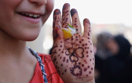 A girl shows a piece of candy with her hand painted with henna during the first day of Eid-al Fitr celebration in West Mosul, Iraq June 25, 2017. REUTERS/Erik De Castro