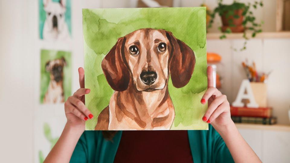 best ways to memorialize your pet — person holding painting of dog