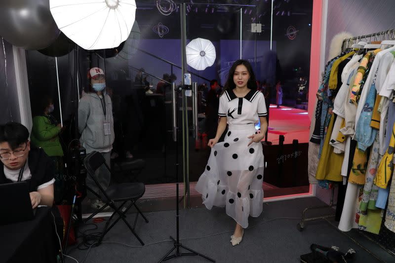 Live streamer promotes a dress by XUNRUO during a live streaming session, inside a booth set up at a show venue during China Fashion Week, in Beijing