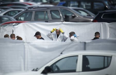 Crash investigors inspect the site of an airplane crash at the British Car Auctions lot next to Blackbushe Airport, near Camberley, in southern Britain August 1, 2015. REUTERS/Luke MacGregor