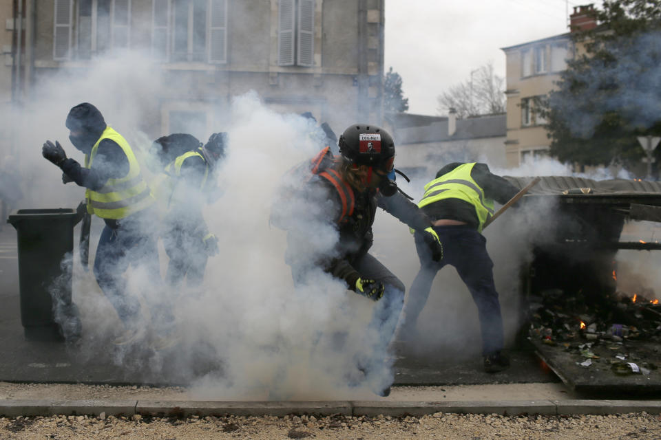 La policía francesa rocía gas lacrimógeno a los manifestantes chalecos amarillos que montaron barricadas en Bourges, Francia, el sábado 12 de enero de 2019. (AP Foto/Rafael Yaghobzadeh)