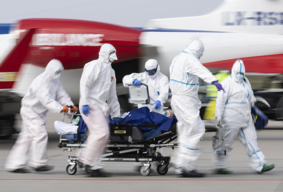 A patient from France who is seriously ill with the coronavirus is transported from an ambulance plane after landing at Dresden International Airport in Dresden, Germany, Saturday, April 4, 2020. For most people, the new coronavirus causes only mild or moderate symptoms, such as fever and cough. For some, especially older adults and people with existing health problems, it can cause more severe illness, including pneumonia.(Robert Michael/dpa via AP)