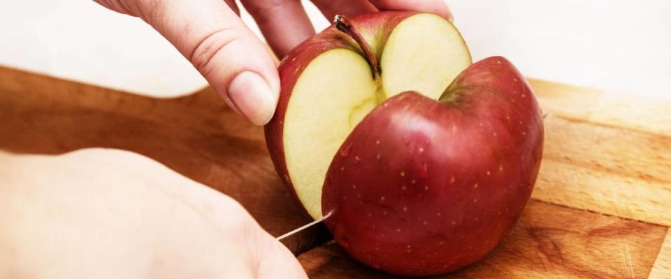 The girl is cutting apple on the cutting board