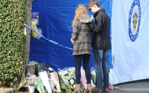 Lydia Wilkinson, the daughter of stabbing victims Peter and Tracey Wilkinson, views floral tributes with her boyfriend at her family home in Stourbridge - Credit: Rui Vieira/PA