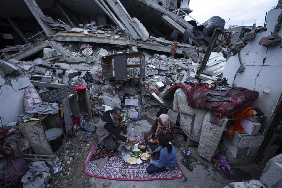 Members of the Al-Rabaya family break their fast during the Muslim holy month of Ramadan outside their destroyed home by the Israeli airstrikes in Rafah, Gaza Strip, Monday, March 18, 2024. (AP Photo/Fatima Shbair)