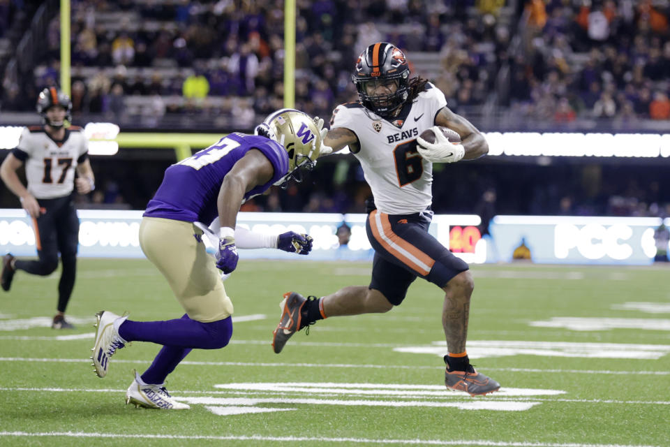 Oregon State running back Damien Martinez (6) runs with the ball and pushes off Washington cornerback Mishael Powell (23) during the first half of an NCAA college football game Friday, Nov. 4, 2022, in Seattle. (AP Photo/John Froschauer)