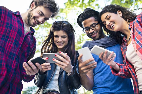 4 friends gathered around their mobile phones