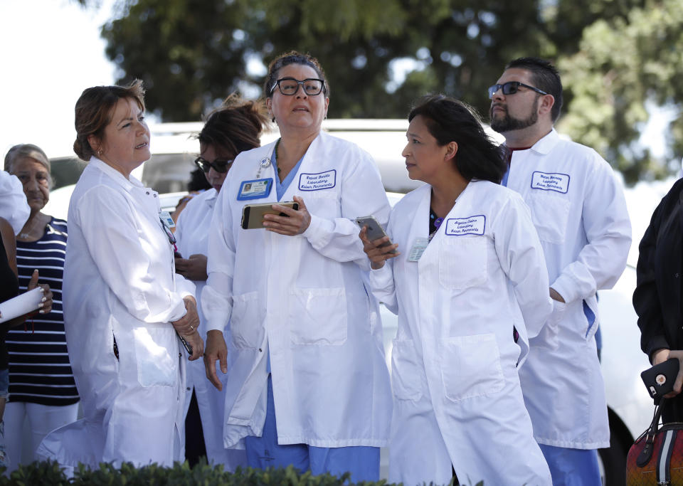 Hospital staff wait outside after they were evacuated from Kaiser Permanente Downey Medical Center, following reports of someone with a weapon at the facility in Downey, Calif., Tuesday, Sept. 11, 2018. Los Angeles County sheriff's officials say a suspect is in custody and deputies and police officers are methodically searching the complex. (AP Photo/Jae C. Hong)