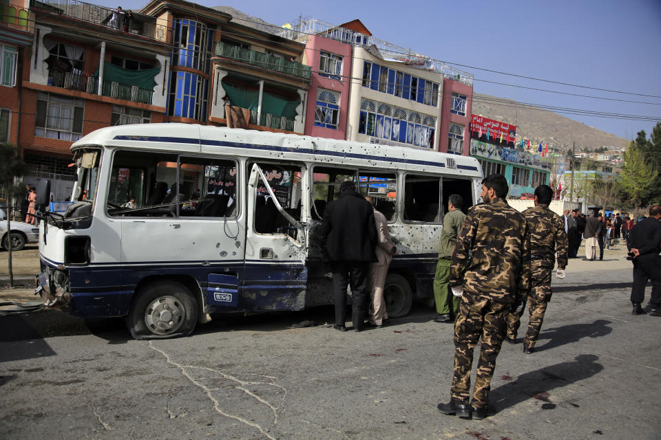Security personnel inspect a damaged minibus after a bomb explosion in Kabul Afghanistan, Thursday, March 18, 2021. The bus attack caused numerous deaths and injuries according to police. (AP Photo/Mariam Zuhaib)