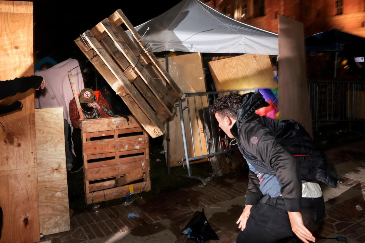 <span>A counter-protester throws a crate at a pro-Palestinian encampment at UCLA on 1 May.</span><span>Photograph: Wally Skalij/Los Angeles Times via Getty Images</span>