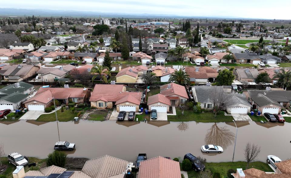 In an aerial view, homes are seen surrounded by floodwaters on Wednesday, Jan. 11, 2023 in Planada, California. The Central Valley town was devastated by widespread flooding after a severe atmospheric river event moved through the area earlier in the week. The San Francisco Bay Area and much of California continues to be drenched by powerful atmospheric river events that have brought high winds and flooding rains. The storms have toppled trees, flooded roads and cut power to tens of thousands.