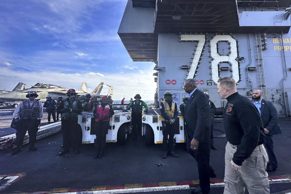 Defense Secretary Lloyd Austin, front left, walks next to the commanding officer of the USS Gerald R. Ford, Navy Capt. Rick Burgess, front, during an unannounced visit to the ship on Wednesday, Dec. 20, 2023. The USS Gerald R. Ford has been sailing just a few hundred miles off the coast of Israel to prevent the Israel-Hamas war from expanding into a regional conflict. (AP Photo/Tara Copp)