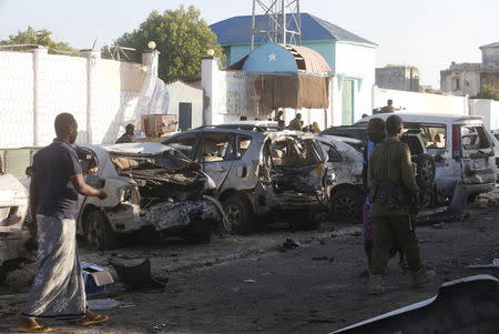 A policeman and residents walk past the wreckage of cars destroyed in a car bomb attack outside beachside restaurant Beach View Cafe on Lido beach, in Somalia's capital Mogadishu, January 22, 2016. REUTERS/Feisal Omar