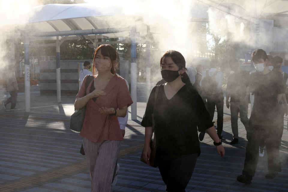 TOKYO, JAPAN  JULY 16, 2021: Locals stand at a bus stop spraying air cooling mist. Valery Sharifulin/TASS (Photo by Valery Sharifulin\TASS via Getty Images)