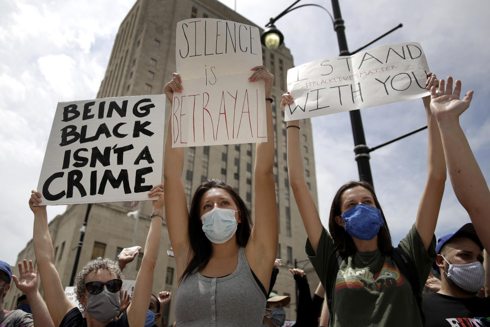 FILE - In this June 5, 2020, file photo, people hold signs during a rally in downtown Kansas City, Mo., to protest the death of George Floyd who died after being restrained by Minneapolis police officers on May 25. As a new generation steps up, activists and historians believe there’s important work to be done for white people: Listening to black voices and following rather than trying to lead, for one, and the deep introspection it takes to confront unconscious bias and the perks of privilege that come just from being white. (AP Photo/Charlie Riedel)