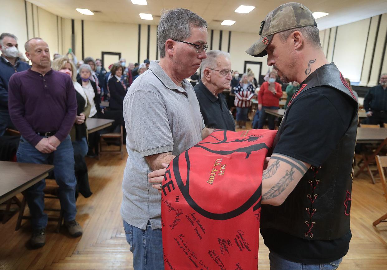 Chris Collins, with the KIA Honor Flag Organization, presents a signed KIA flag to the nephews of Army Sgt. Vernon Judd, a Korean War POW who died in North Korea in 1951. Ken Judd Jr., left, and Bill Moder accepted the flag during a ceremony Saturday at the American Legion Post 221 in Massillon.