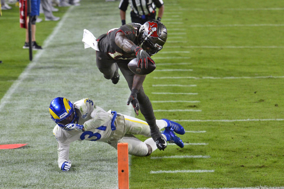 Tampa Bay Buccaneers wide receiver Chris Godwin (14) reaches for the goal line after leaping over Los Angeles Rams defensive back Darious Williams (31) for a touchdown during the second half of an NFL football game Monday, Nov. 23, 2020, in Tampa, Fla. (AP Photo/Jason Behnken)