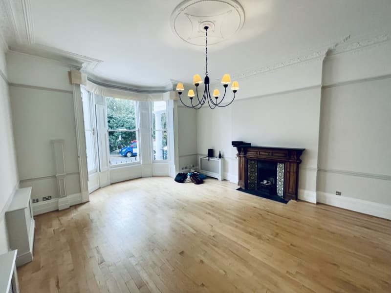 Living room before with white walls, bay windows, and wood mantle.