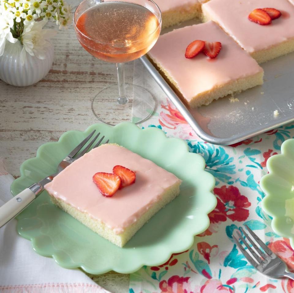 strawberries and rose sheet cake slice on pastel green plate with glass of rose wine