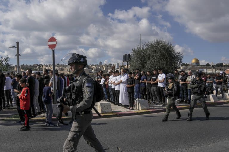 Musulmanes palestinos, a quienes se les prohibió ir a la Mezquita Al-Aqsa en Jerusalén, rezan afuera de la Ciudad Antigua de Jerusalén mientras soldados israelíes montan guardia el 17 de noviembre de 2023