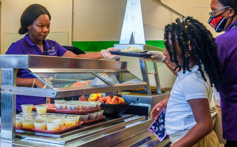 Iiesha Brown, left, hands a meal tray to her colleague Shirley Holmes as a third-grader mulls over which fruit they want for lunch on Monday, Aug. 15, 2022 on the first day of school at Port Royal Elementary. This is Beaufort County School District’s first year with food service vendor The Nutrition Group where parents can use an online app that will alert the district to any food allergies their child may have.