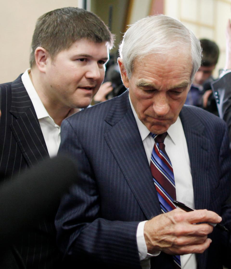 In this Dec. 29, 2011 file photo, then-Republican presidential candidate, Rep. Ron Paul, R-Texas, listens as campaign chairman Jesse Benton, left, has a word with him as he signs autographs in Atlantic, Iowa.