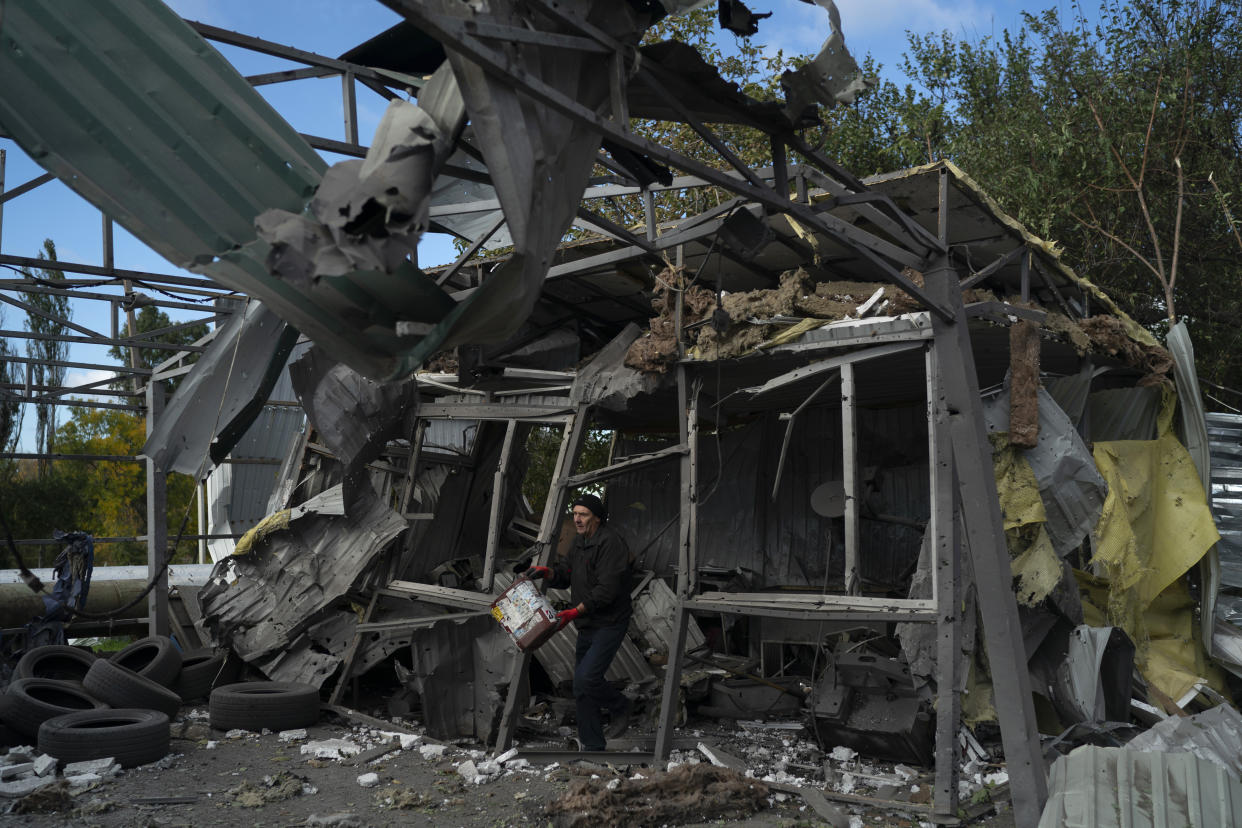 FILE - A man carries a bucket of water to extinguish the remains of a fire in the remains of a car shop that was destroyed after a Russian attack in Zaporizhzhia, Ukraine, Tuesday, Oct. 11, 2022. Russia has declared its intention to increase its targeting of Ukraine’s power, water and other vital infrastructure in its latest phase of the nearly 8-month-old war. (AP Photo/Leo Correa, File)