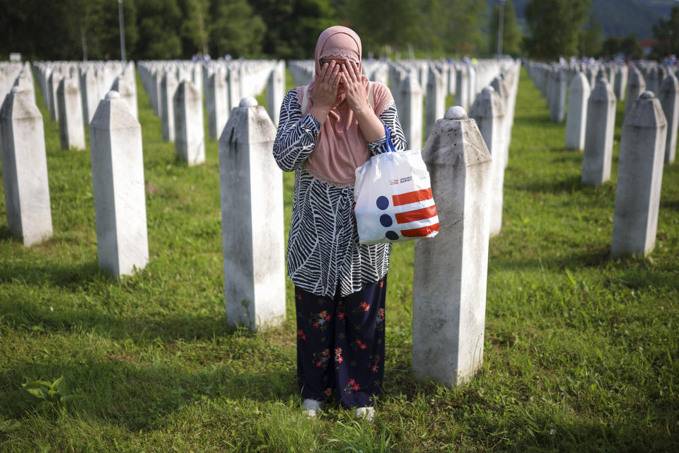 A Bosnian muslim woman prays next to the grave of her relative, victim of the Srebrenica genocide, at the Memorial Centre in Potocari, Bosnia, Tuesday, July 11, 2023. Thousands gather in the eastern Bosnian town of Srebrenica to commemorate the 28th anniversary on Monday of Europe's only acknowledged genocide since World War II. (AP Photo/Armin Durgut)