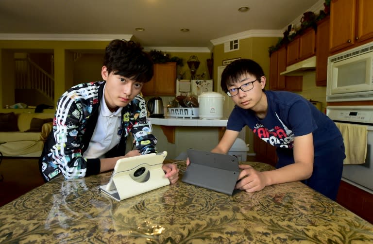 Chinese students Tony Lu and Henry Li (R) spend their free time connected to China on their Internet devices at their host family's home in Murrieta, California on March 23, 2016