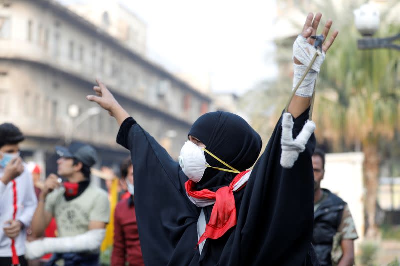 An Iraqi woman demonstrator holds a slingshot during the ongoing anti-government protests, in Baghdad
