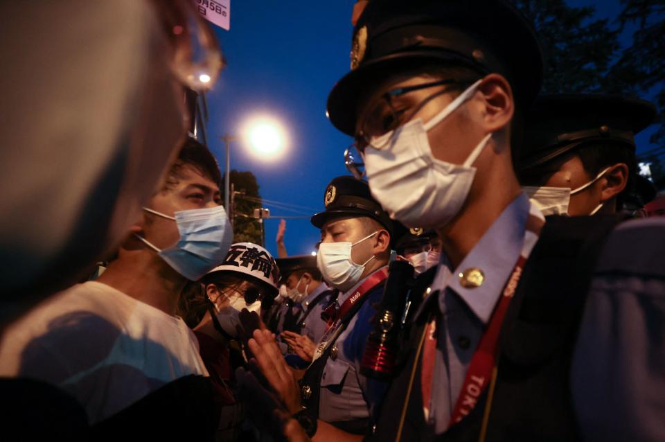 Police officers talk with protestors outside the Olympic Stadium ahead of the opening ceremony of the Tokyo 2020 Olympic Games, in Tokyo, on July 23, 2021. (Photo by Behrouz MEHRI / AFP) (Photo by BEHROUZ MEHRI/AFP via Getty Images)