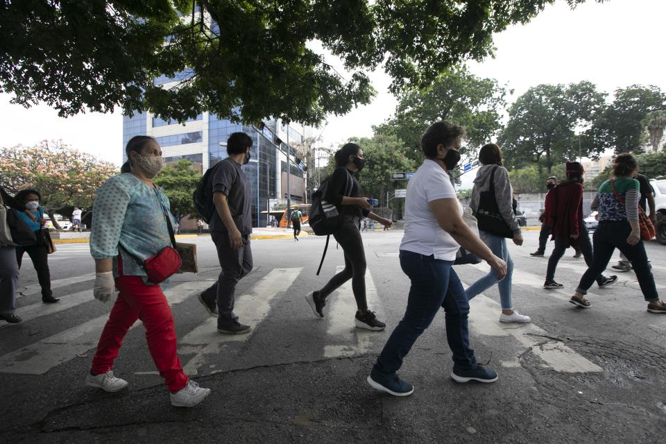 Pedestrians wear face masks amid the new coronavirus pandemic in Caracas, Venezuela, Monday, June 1, 2020. After two and a half months of COVID-19 related quarantine, some industries are allowed to reactivate under a scheme of five days' work and 10 days rest. (AP Photo/Ariana Cubillos)