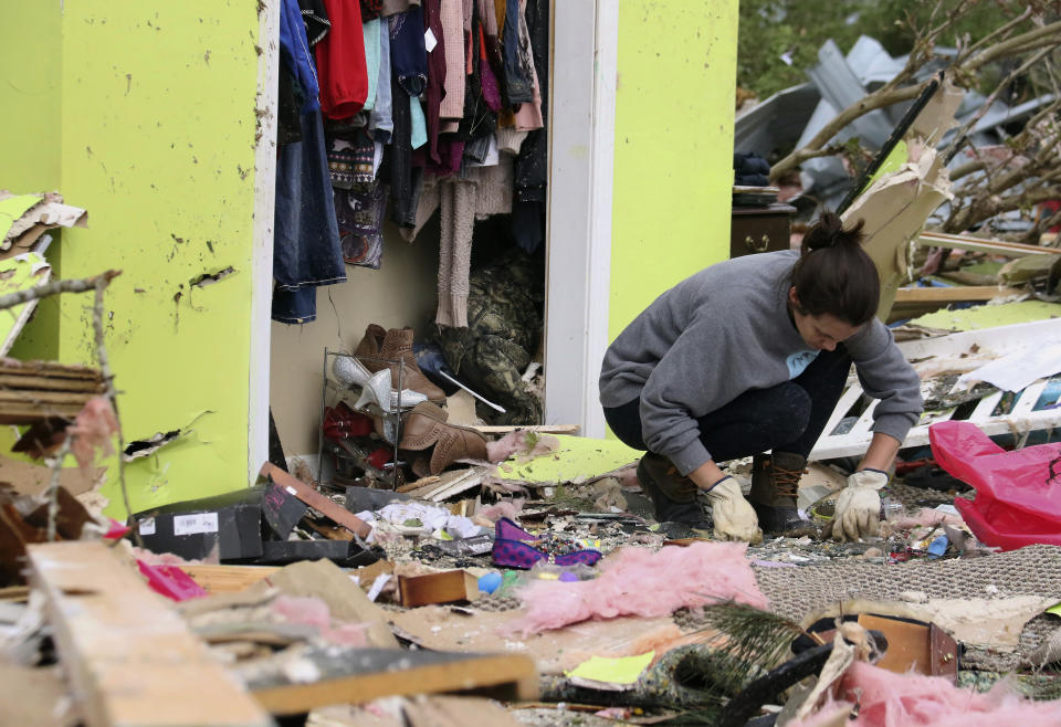 Leslie Harrington kneels down to help a former neighbor and family friend look for jewelry in her destroyed home along Seely Drive outside of Hamilton, Miss., after a deadly storm moved through the area on Sunday, April 14, 2019. (AP Photo/Jim Lytle)