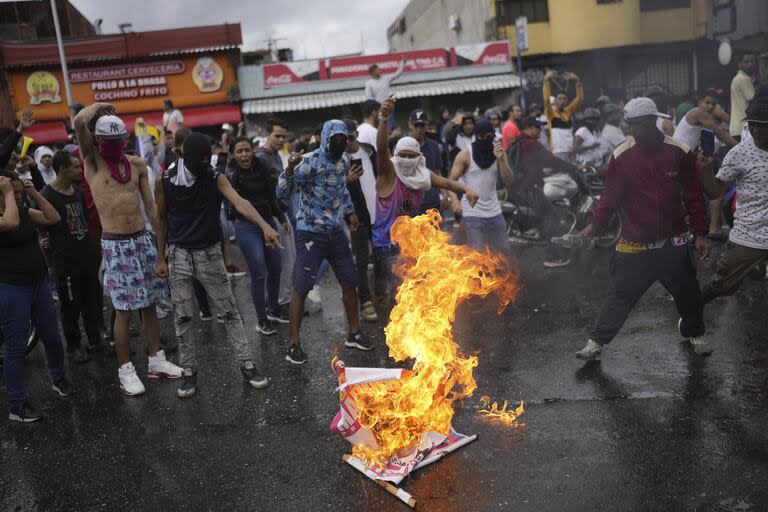 Los manifestantes queman un cartel de campaña electoral del presidente Nicolás Maduro en Caracas.