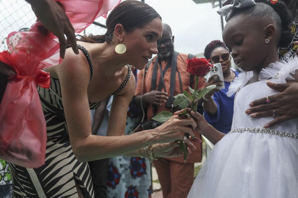 topshot britains meghan c, duchess of sussex, receives flowers from a girl upon her arrival with britains prince harry unseen, duke of sussex, for an exhibition sitting volleyball match at nigeria unconquered, a local charity organisation that supports wounded, injured, or sick servicemembers, in abuja on may 11, 2024 as they visit nigeria as part of celebrations of invictus games anniversary photo by kola sulaimon afp photo by kola sulaimonafp via getty images