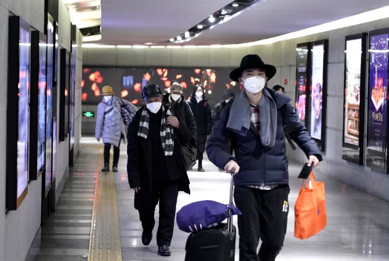 People wearing masks walk through an underground passage to the subway in Beijing