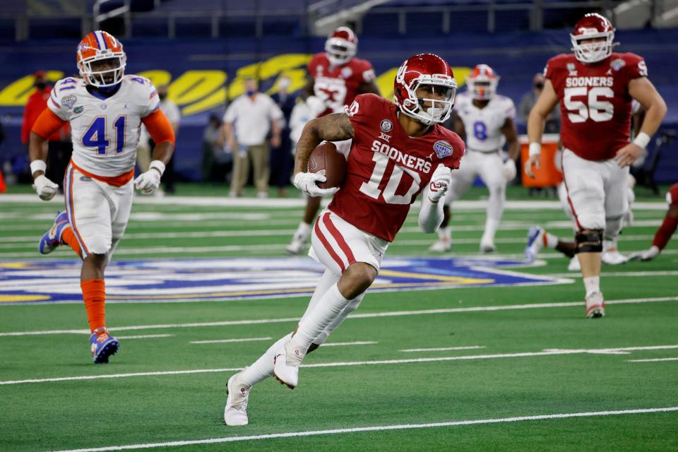Oklahoma wide receiver Theo Wease (10) sprints to the end zone after a reception and scores a touchdown, ahead of Florida linebacker James Houston IV (41) during the first half of the Cotton Bowl NCAA college football game in Arlington, Texas, Wednesday, Dec. 30, 2020. (AP Photo/Michael Ainsworth)