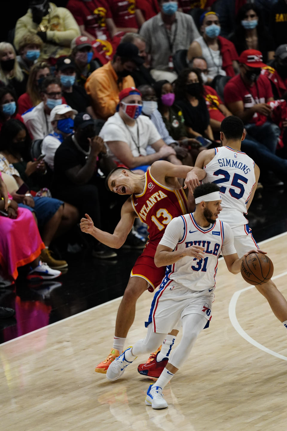 Philadelphia 76ers guard Seth Curry (31) carries the ball as Philadelphia 76ers guard Ben Simmons (25) clashes with Hawks guard Bogdan Bogdanovic (13) during the second half of Game 3 of a second-round NBA basketball playoff series, Friday, June 11, 2021, in Atlanta. (AP Photo/John Bazemore)