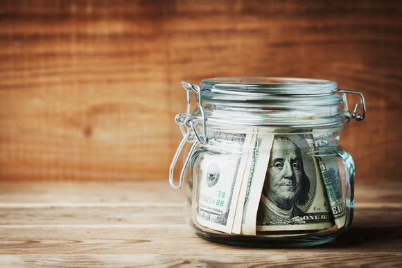 Image of $100 bills in jar sitting on table.