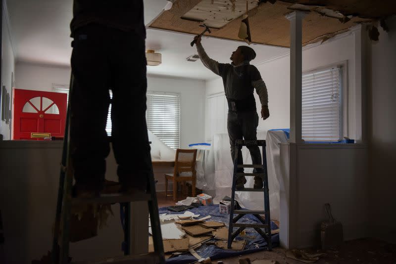 FILE PHOTO: Contractors remove material from a ceiling in a recently-purchased home in Houston