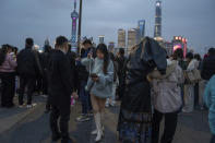 A woman looks at her phone on a selfie stick on the bund, a historic riverside district of Shanghai known for its Western architecture on March 18, 2024. (AP Photo/Ng Han Guan)