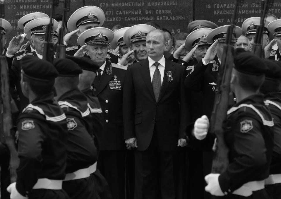Russian President Vladimir Putin, surrounded by saluting military officers, attends a parade.