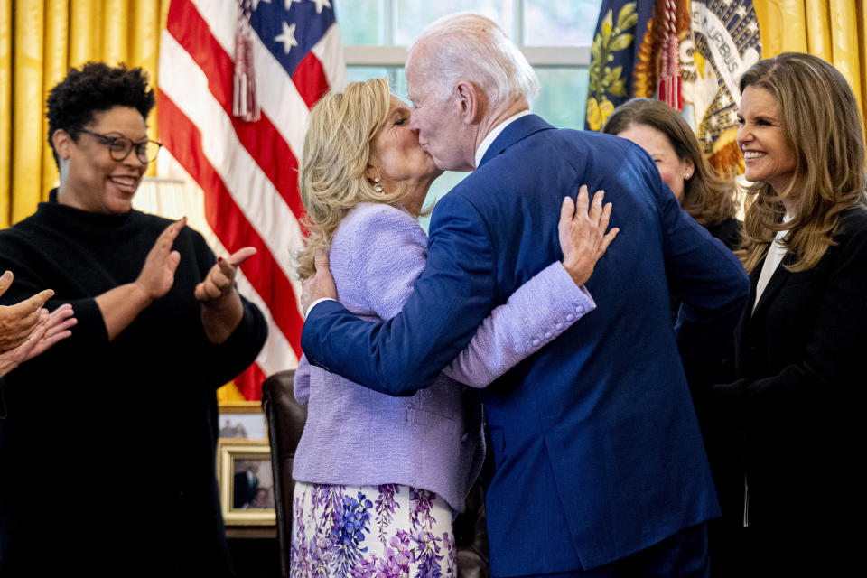 President Joe Biden, accompanied by Office of Management and Budget director Shalanda Young, left, and Women's Alzheimer's Movement and former First Lady of California Maria Shriver, right, gives first lady Jill Biden a kiss after giving her the pen he used to sign a presidential memorandum that will establish the first-ever White House Initiative on Women's Health Research in the Oval Office of the White House, Monday, Nov. 13, 2023, in Washington. (AP Photo/Andrew Harnik)