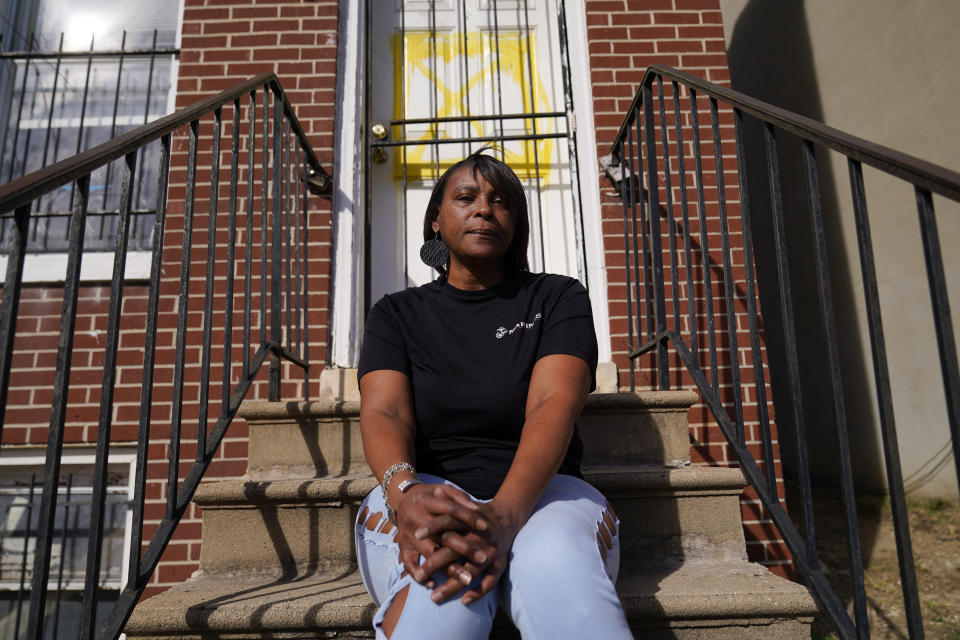 Angela Banks poses for a photograph in front of the house she used to rent, Wednesday, Feb. 15, 2023, in Baltimore. In 2018, Banks was told by her landlord that Baltimore officials were buying her family's home of four decades, planning to demolish the three-story brick rowhouse to make room for an urban renewal project aimed at transforming their historically Black neighborhood. Banks and her children became homeless almost overnight. Banks filed a complaint Monday asking federal officials to investigate whether Baltimore's redevelopment policies are perpetuating racial segregation and violating fair housing laws by disproportionately displacing Black and low-income residents. (AP Photo/Julio Cortez)