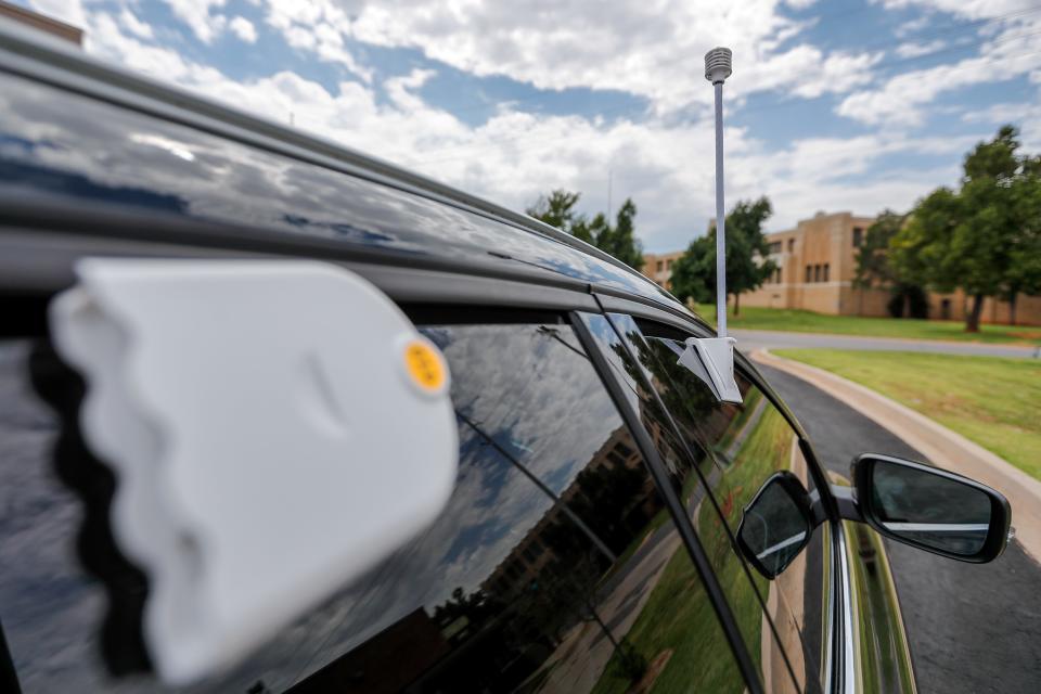 Liz Bowman places a sensor on her car Saturday as planners, scientists and volunteers undertaking a federally funded attempt to map the hottest areas of Oklahoma City.