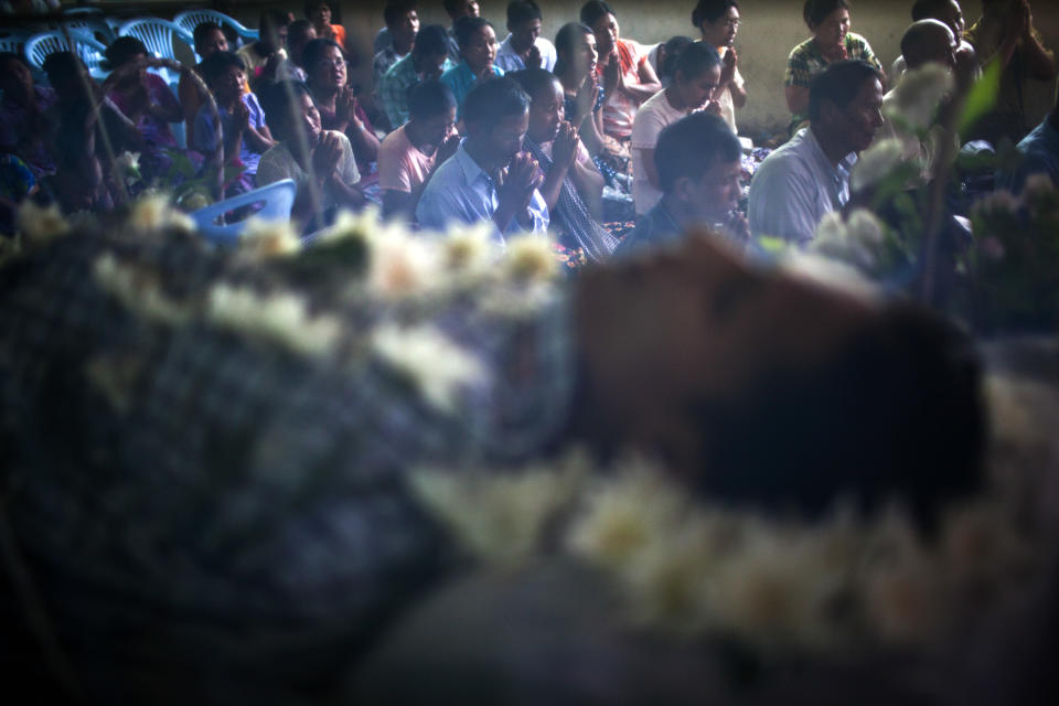 In this Sept. 4, 2012 photo, relatives and friends, seen through a net shield covering the body of Kyaw Naing Aung, 29, who died a day earlier from AIDS, offer prayers during a funeral on the outskirts of Yangon, Myanmar. Myanmar ranks among the world's hardest places to get HIV care, and health experts warn it will take years to prop up a broken health system hobbled by decades of neglect. (AP Photo/Alexander F. Yuan)