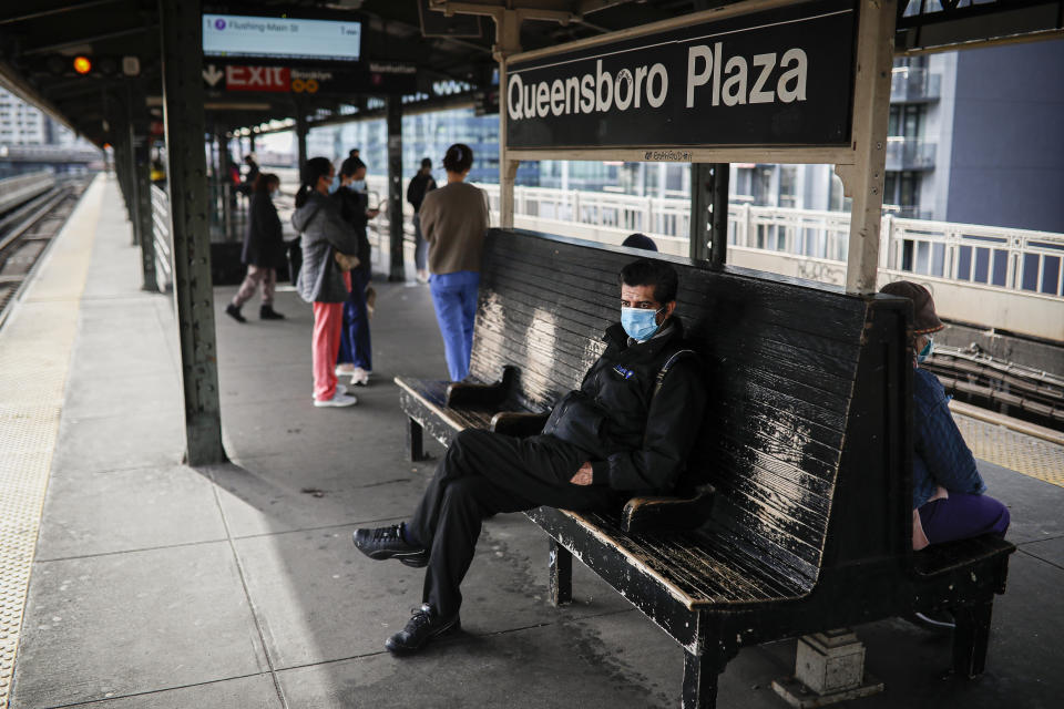 Riders, some wearing face masks due to COVID-19 concerns, wait for a subway train at Queensboro Plaza, Tuesday, April 7, 2020, in the Long Island City neighborhood in the Queens borough of New York. The new coronavirus causes mild or moderate symptoms for most people, but for some, especially older adults and people with existing health problems, it can cause more severe illness or death. (AP Photo/John Minchillo)