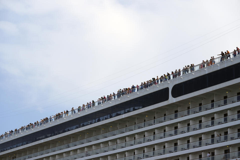 Passengers stand on the deck of the 92,409-ton,16-deck MSC Orchestra cruise ship as it departs from Venice, Italy, Saturday, June 5, 2021. The first cruise ship leaving Venice since the pandemic is set to depart Saturday amid protests by activists demanding that the enormous ships be permanently rerouted out the fragile lagoon, especially Giudecca Canal through the city's historic center, due to environmental and safety risks. (AP Photo/Antonio Calanni)